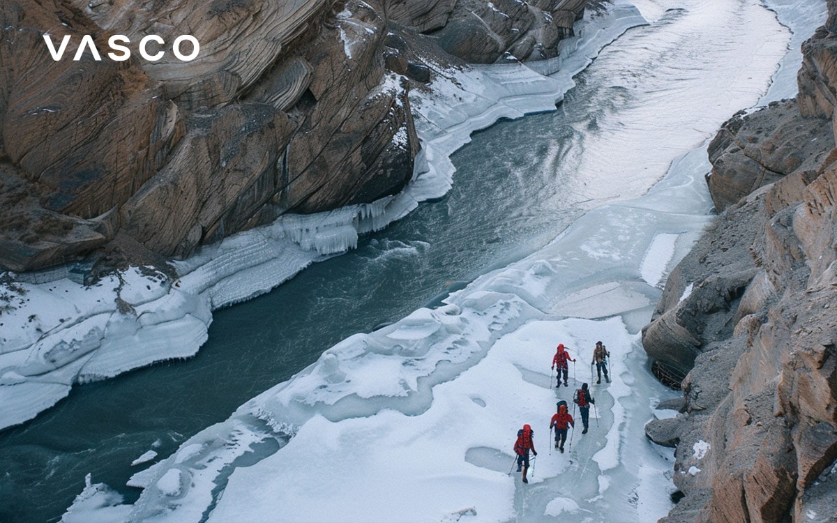 Gruppo di escursionisti camminano su un fiume ghiacciato attraverso un canyon innevato.