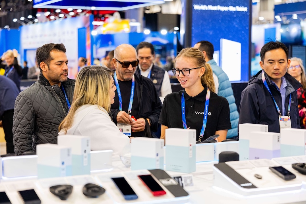 CES 2026 Un gruppo di persone sorridenti chiacchiera allo stand Vasco Electronics al CES 2026.