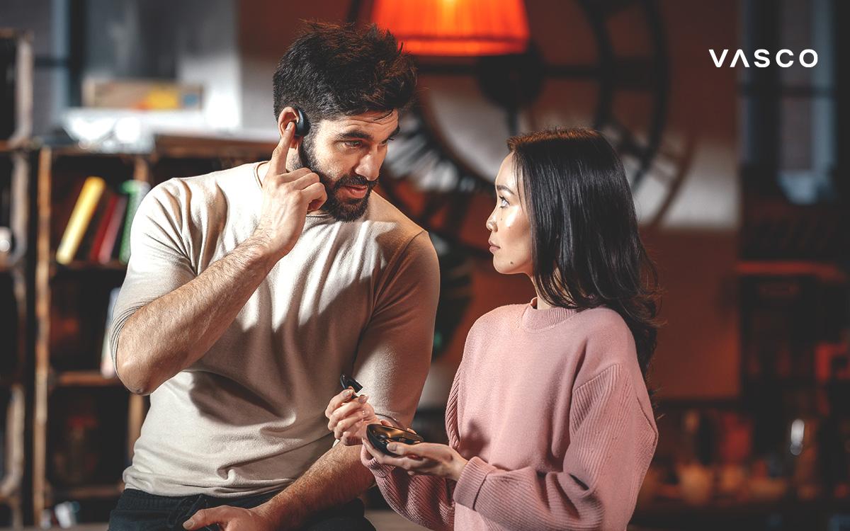 66c7ced2-4d44-4940-9419-7407b82ae6d2 Un uomo e una donna usano auricolari traduttori basati sull’intelligenza artificiale per una conversazione multilingue in tempo reale.