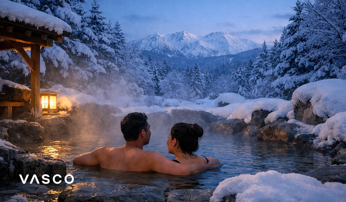 Coppia che si rilassa in un tradizionale onsen giapponese circondato da montagne innevate - viaggio invernale in Giappone