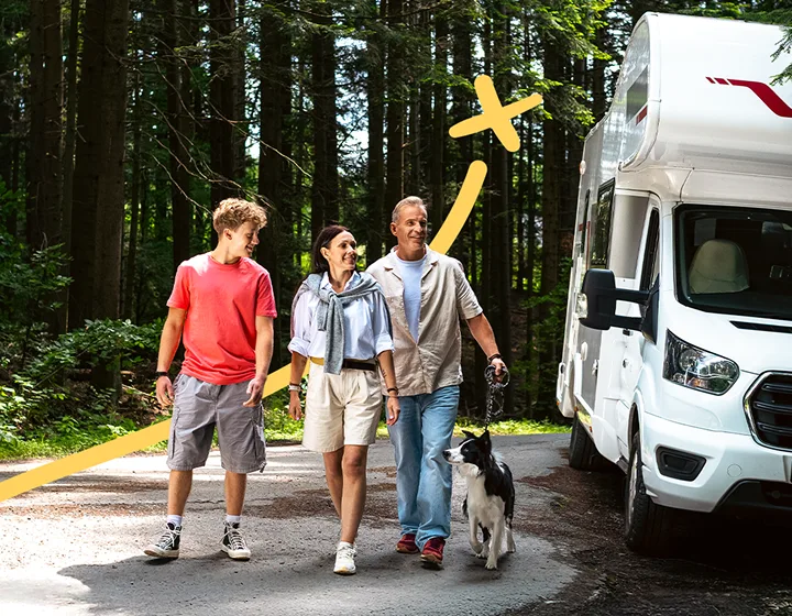 Una famiglia di tre persone – due genitori e un figlio – con un cane, si allontana dal loro camper parcheggiato in una giornata di sole. Sorridono, chiacchierano e si godono la reciproca compagnia.