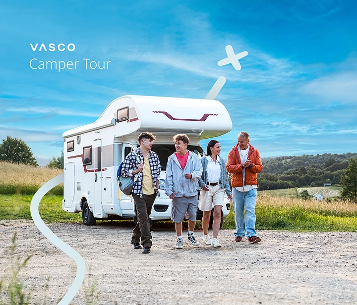 Una famiglia di quattro persone - due genitori e due bambini - si allontana dal camper parcheggiato in una giornata di sole. Sorridono, chiacchierano e si godono la compagnia reciproca, creando un'atmosfera calda e rilassata che riflette la gioia di viaggiare insieme.