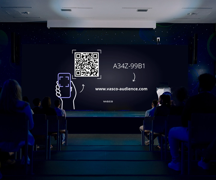Un grande schermo nella sala conferenze mostra le istruzioni "Join Vasco Audience" (Unisciti al pubblico Vasco), fornendo ai partecipanti indicazioni su come accedere alla sessione.