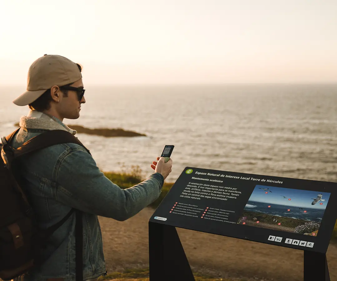 un uomo al bellissimo mare utilizzando un traduttore di foto per leggere un cartello con informazioni turistiche sulla sua posizione